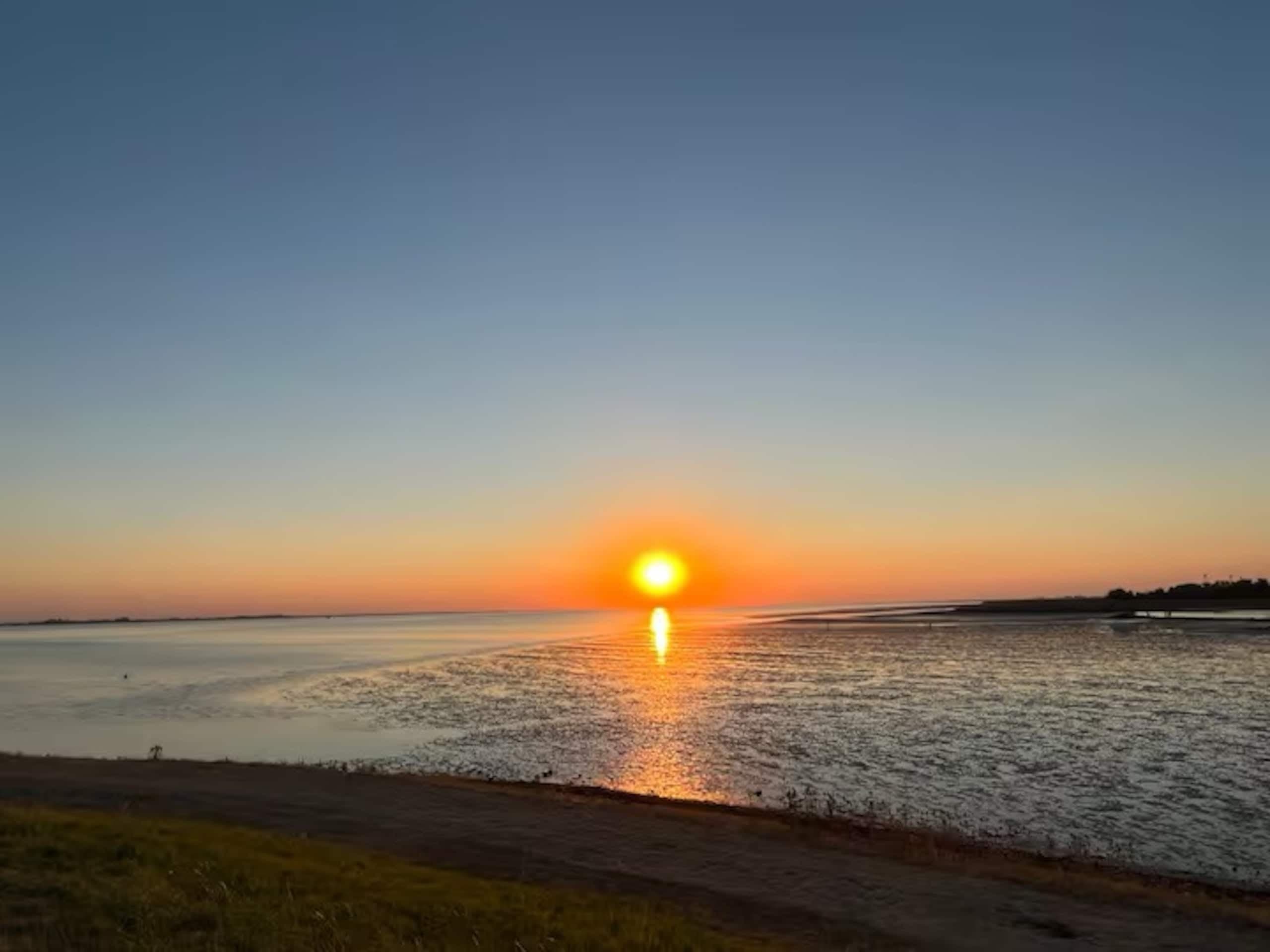 Zonsondergang boven het water bij laag tij